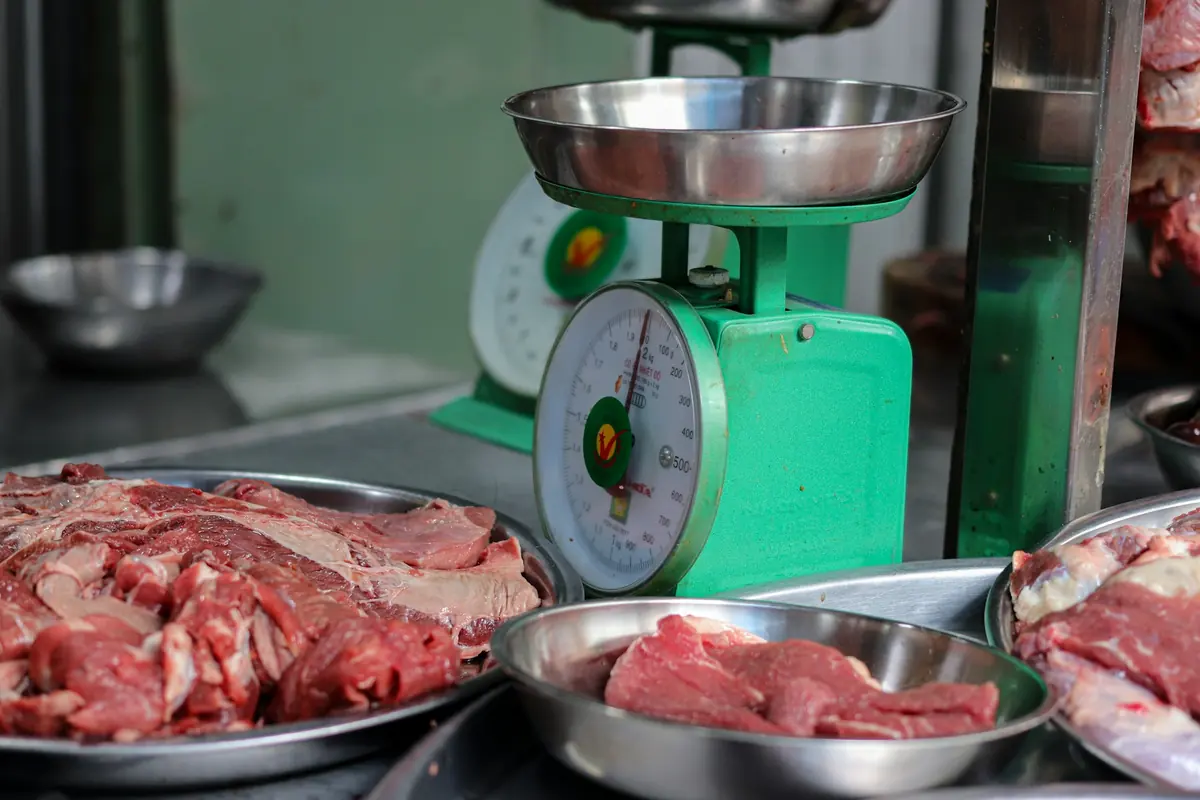 A butcher weighing meat on a shop scale
