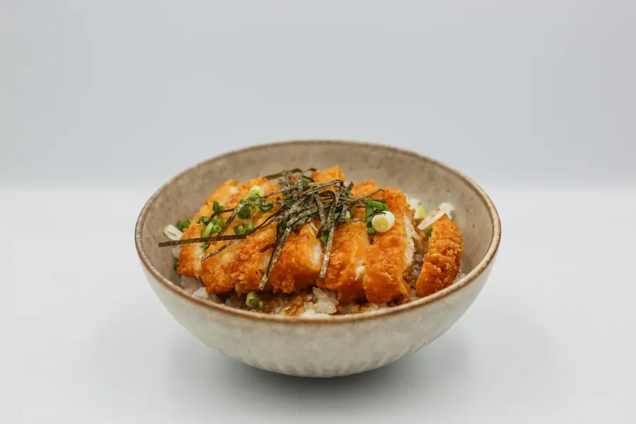 Seasoned rice topped with chicken, salad and white sauce