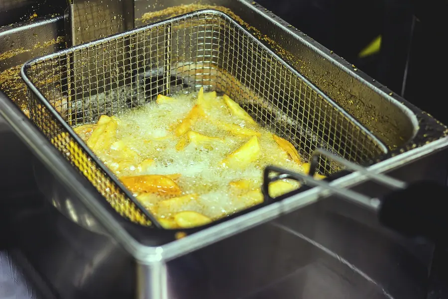 A fryer basket being lowered into hot oil