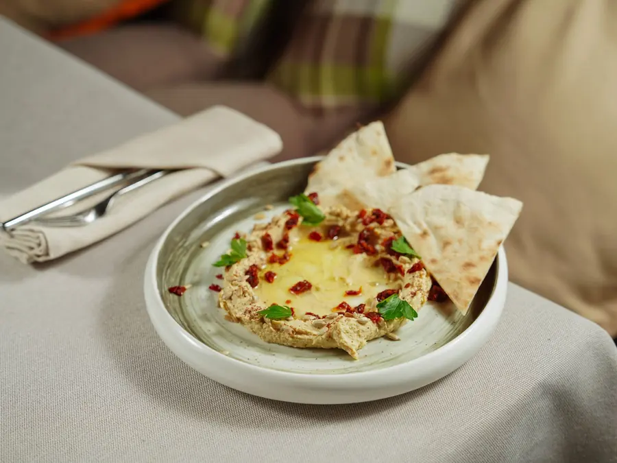 A piece of flatbread being dipped into a bowl of dip