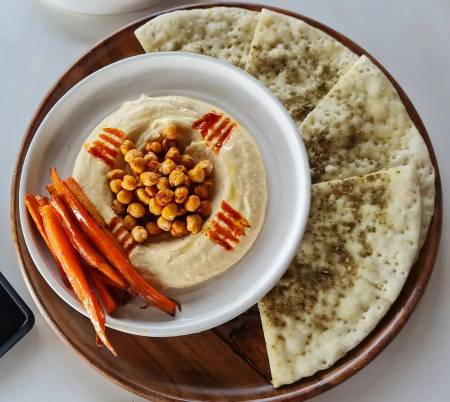 Bowl of hummus with chickpeas, carrots and warm pita bread