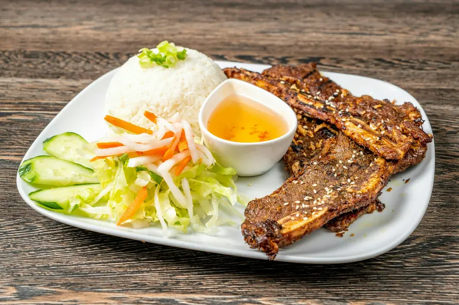 Grilled meat served on a plate with rice and salad