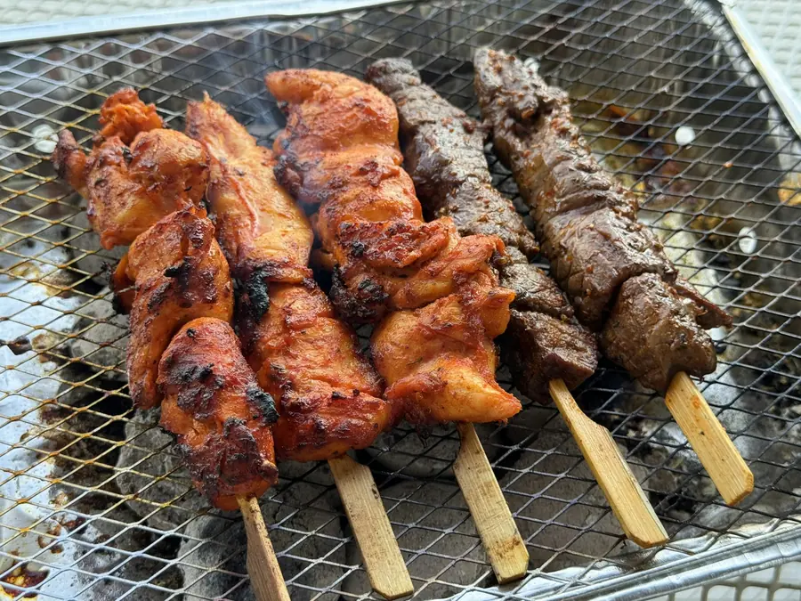 Marinated chicken skewers cooking over charcoal