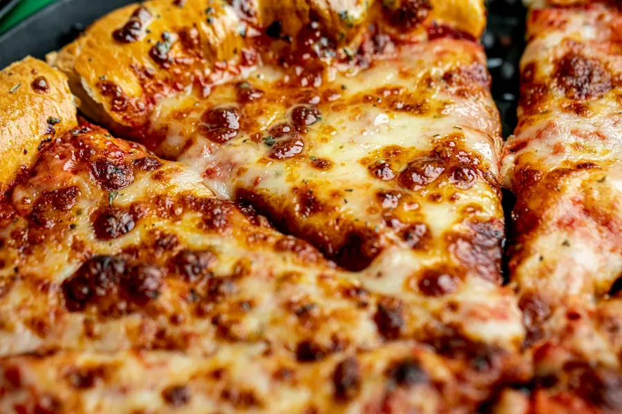 Close-up of melted cheese stretching from a slice of pizza