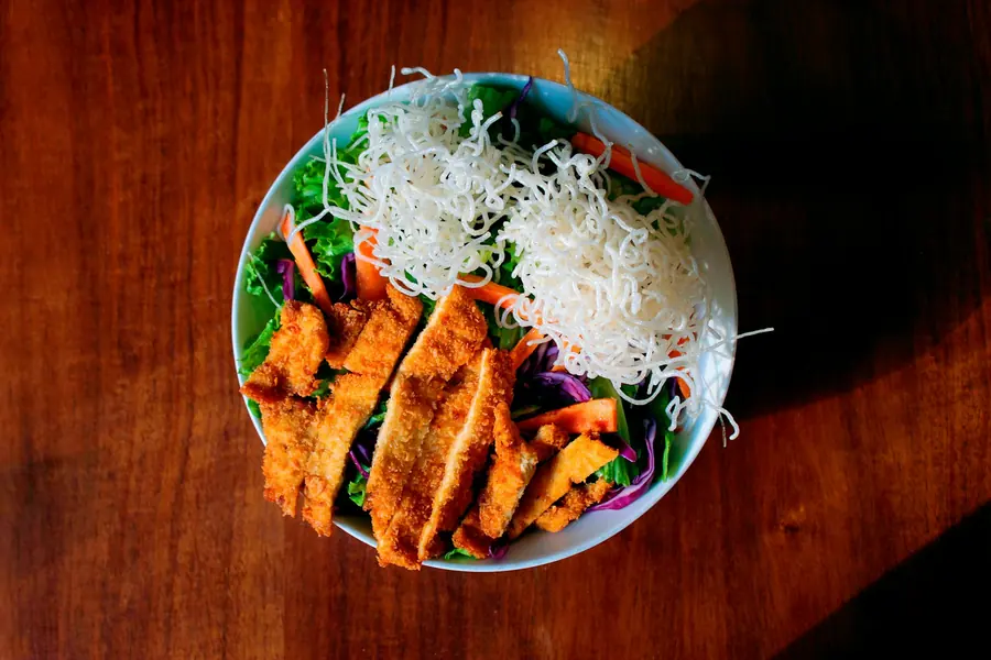 A rice plate topped with sliced meat and salad