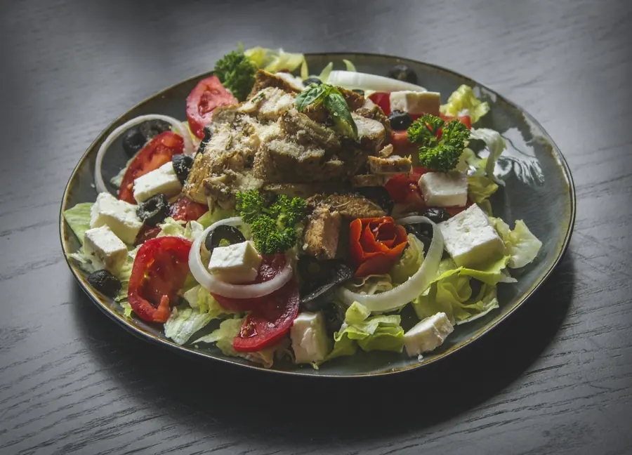 A salad topped with sliced grilled chicken