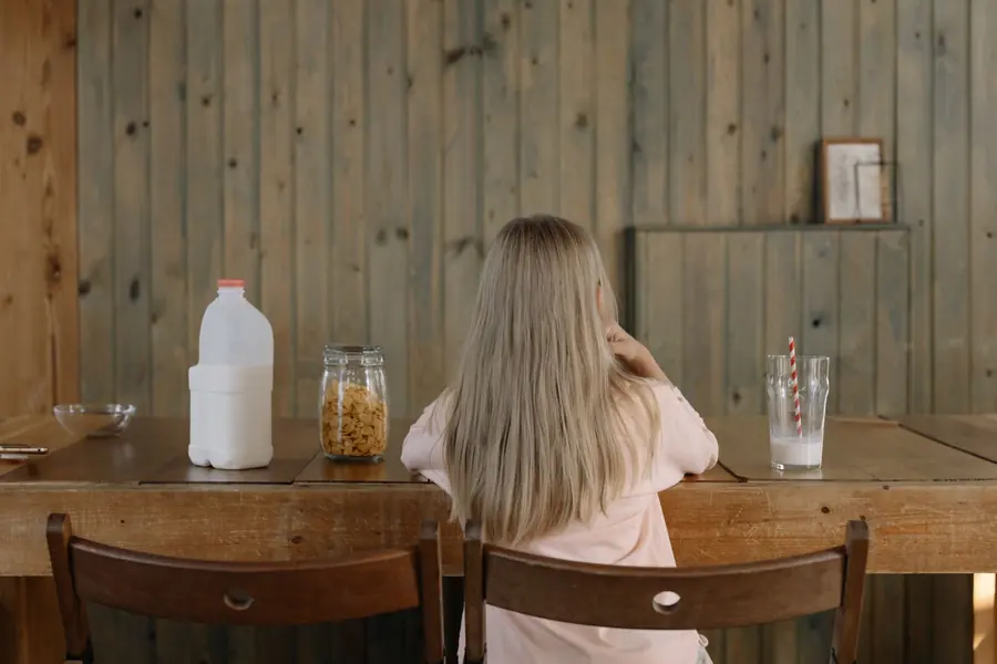 A carton of soy milk beside a glass
