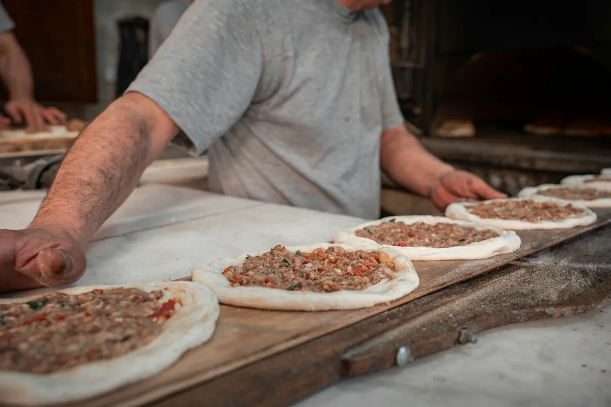 Hands preparing fresh flatbreads by a stone oven