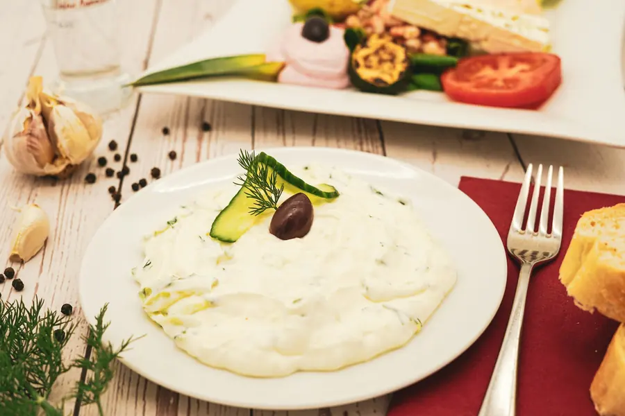A bowl of yogurt and cucumber sauce with fresh dill