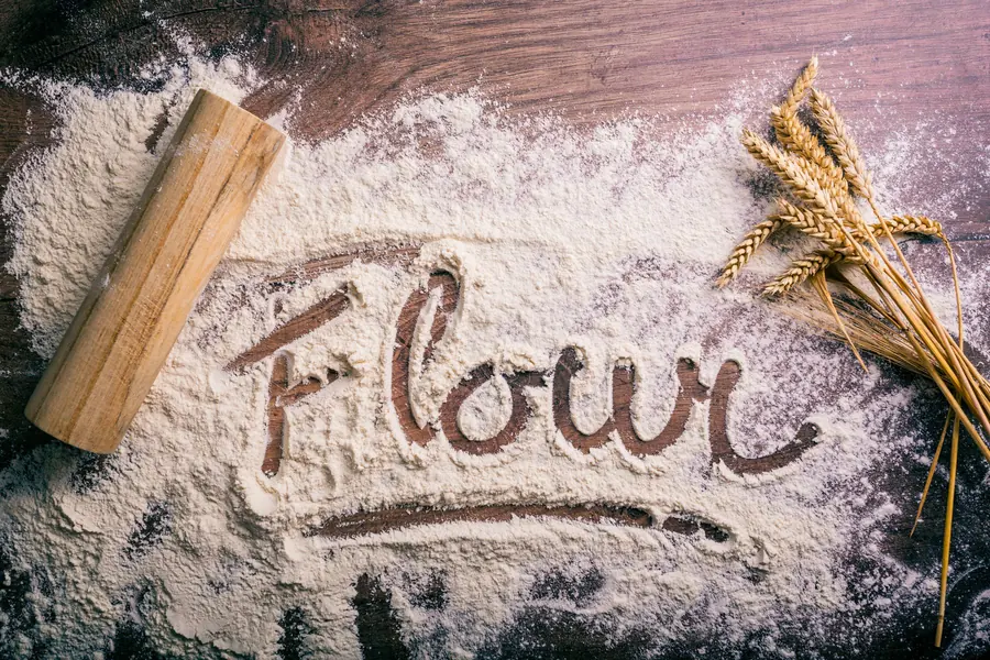 Wheat grain and flour on a wooden surface