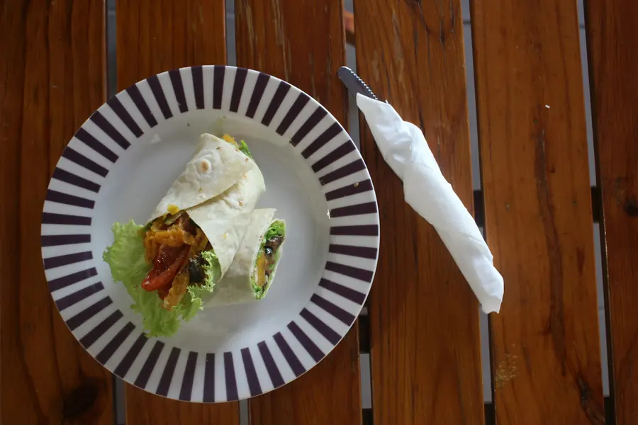 A filled wrap cut in half to show the meat and salad inside